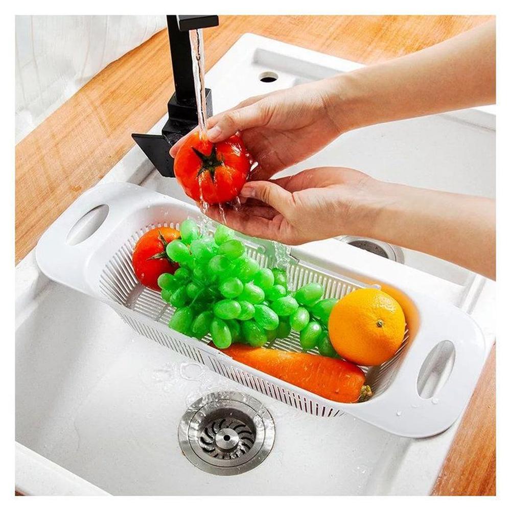 Escurridor retráctil sobre el lavadero frutas verduras vasos cubiertos